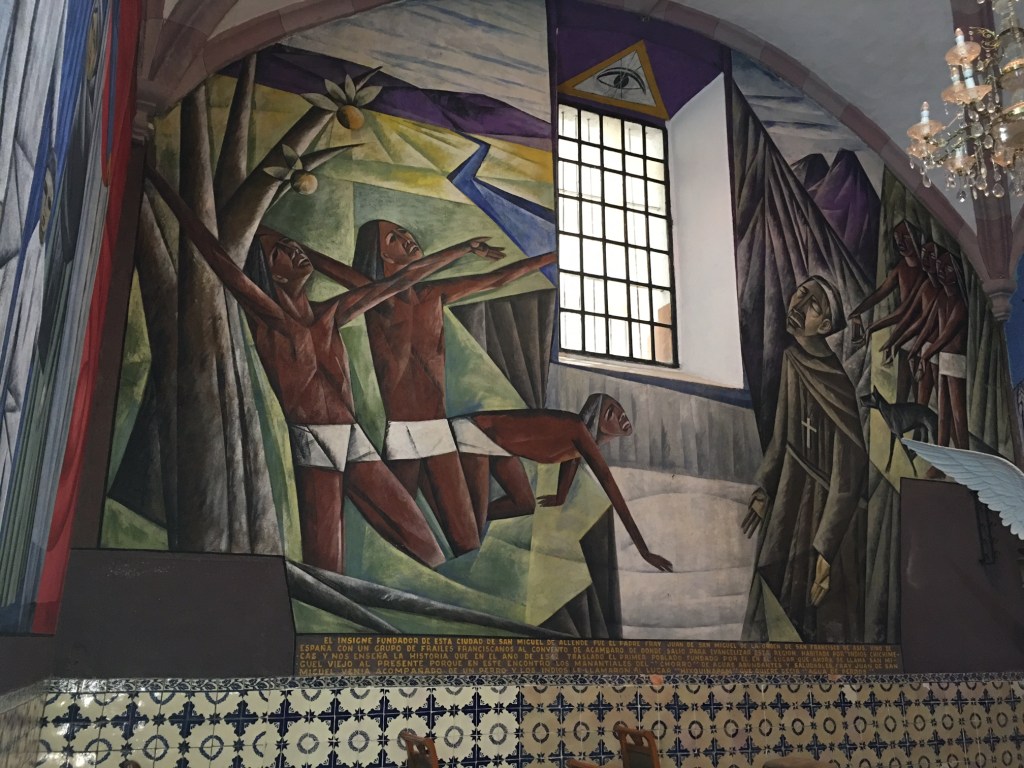 A painting in a San Miguel de Allende church showing Indigenous people kneeling in supplication before a religious friar.